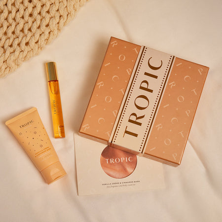 Vanilla Crème & Cinnamon Bark – fine fragrance and body cream set by Tropic Skincare, including body cream, fragrance , and festive gift packaging on a soft blanket background.